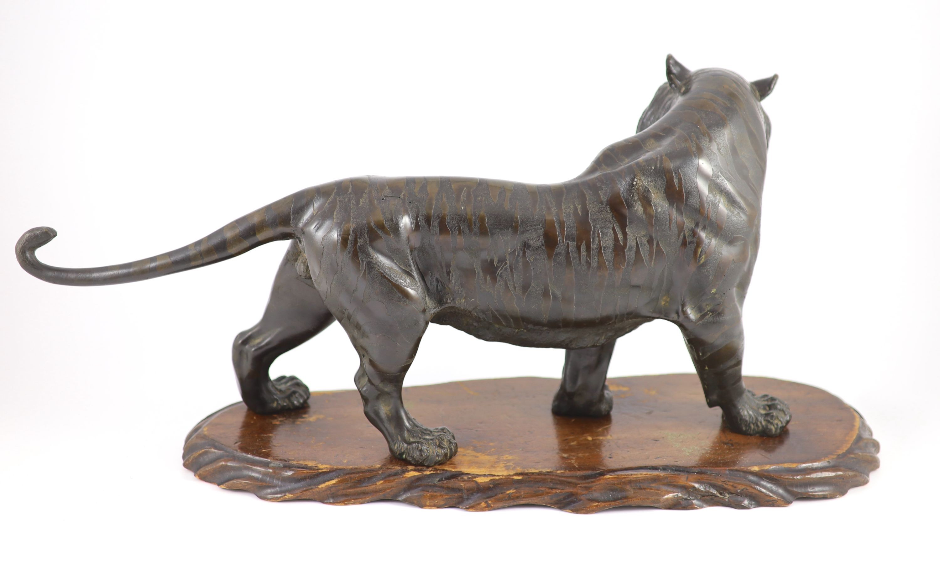 A large Japanese Meiji bronze model of a stalking tiger, Meiji period, 58.5 cm long, wood stand